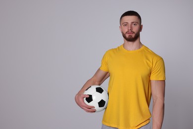 Athletic young man with soccer ball on light grey background. Space for text