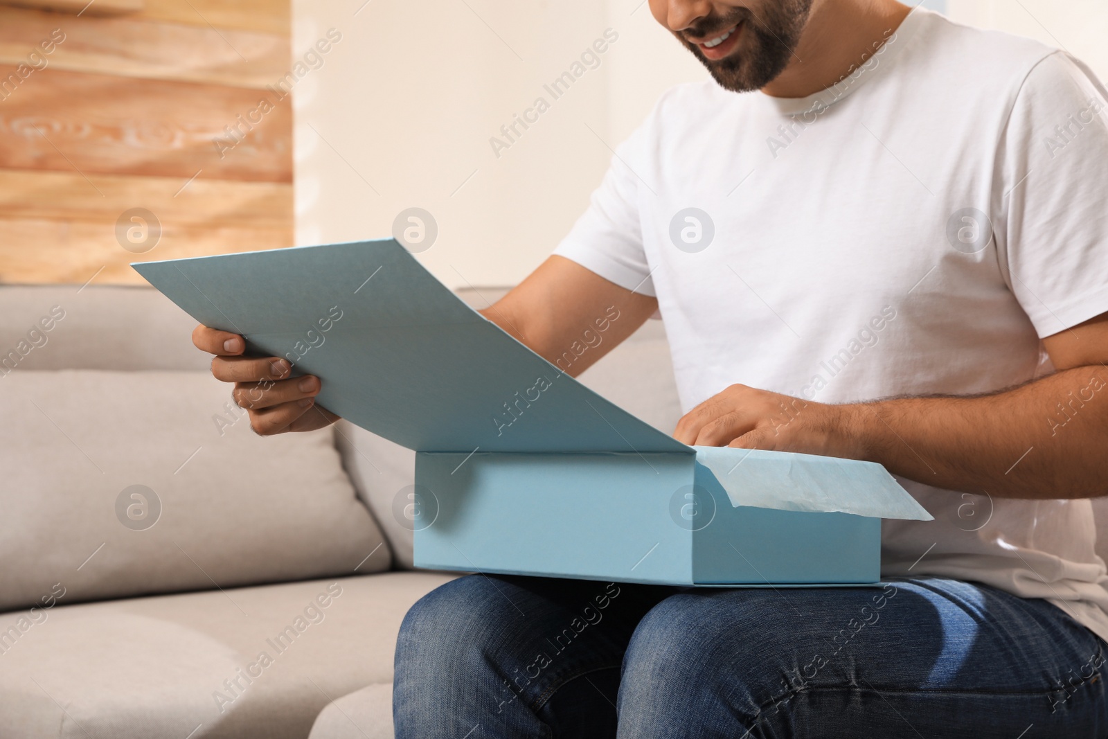 Photo of Man unpacking parcel at home, closeup. Online shopping