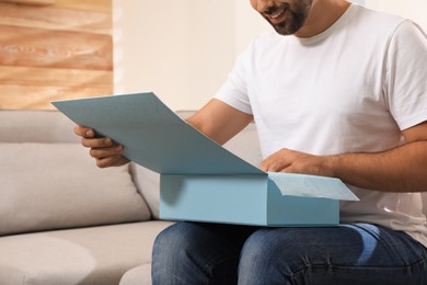 Photo of Man unpacking parcel at home, closeup. Online shopping