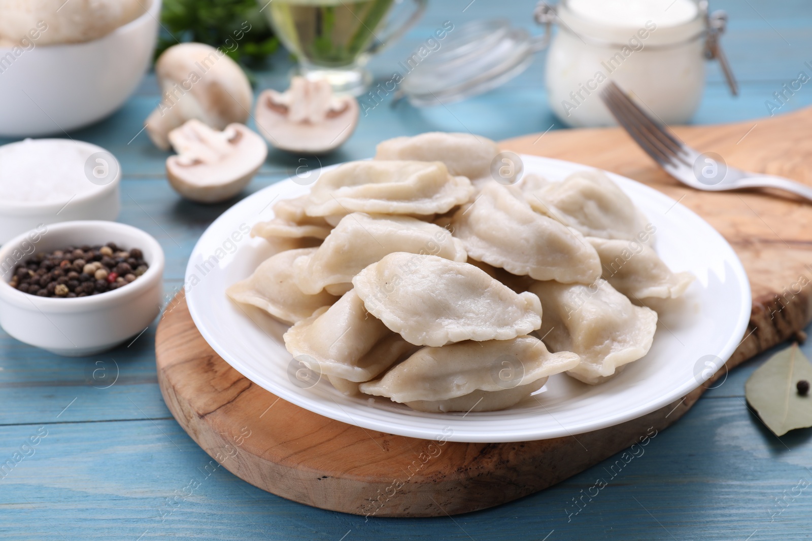 Photo of Delicious dumplings (varenyky) with potatoes served on light blue wooden table