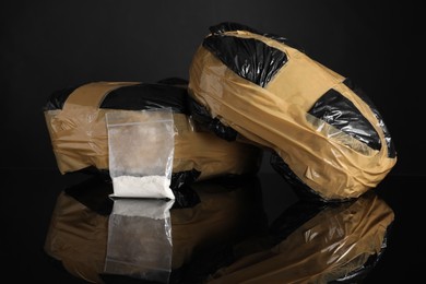 Photo of Smuggling and drug trafficking. Packages with narcotics on black mirror surface