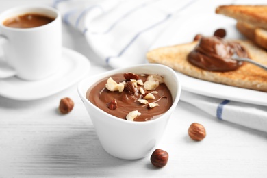 Photo of Chocolate cream with hazelnuts in dessert bowl served on table