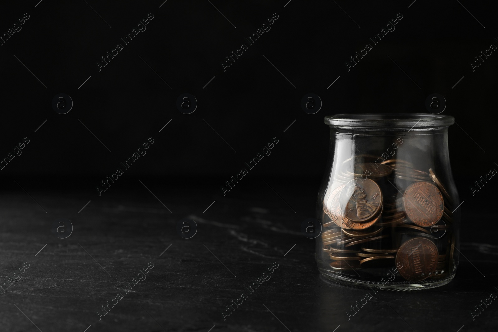 Photo of Glass jar with coins on black table, space for text