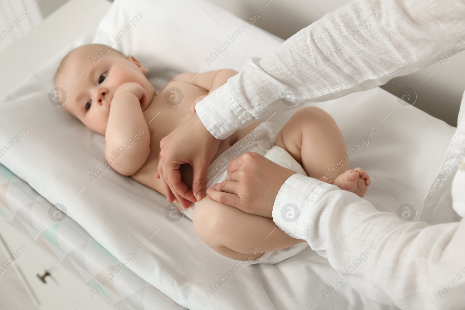 Photo of Mother changing her baby's diaper on table, closeup