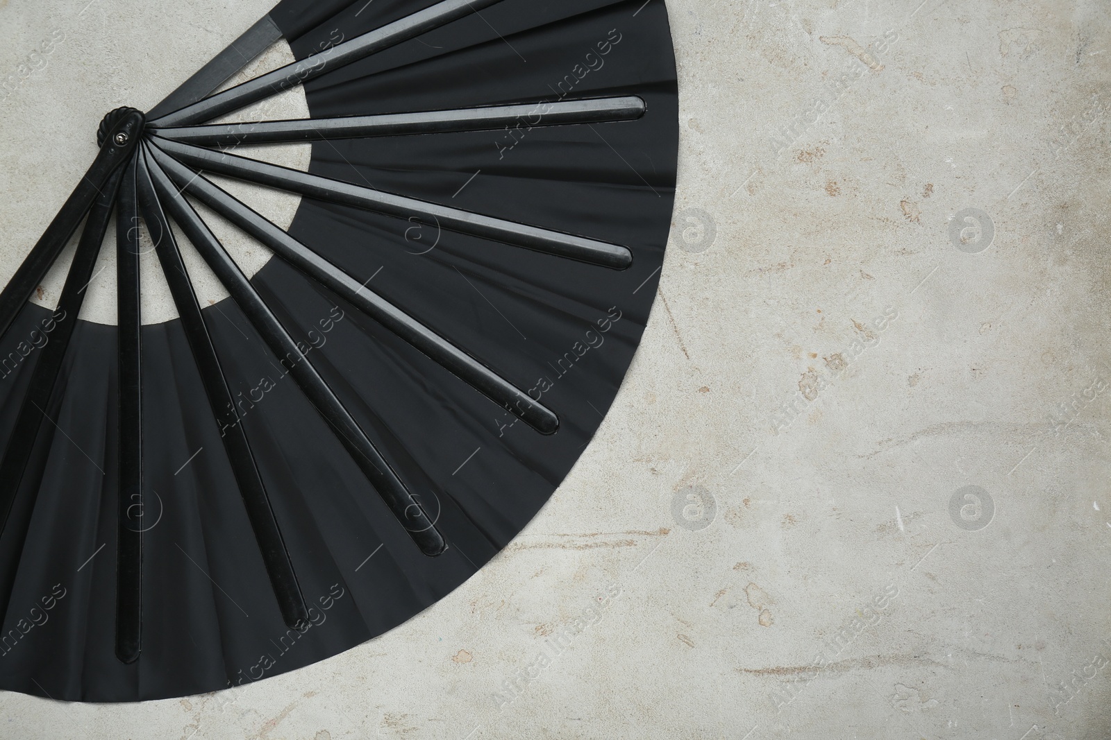 Photo of Stylish black hand fan on old light grey background, top view. Space for text