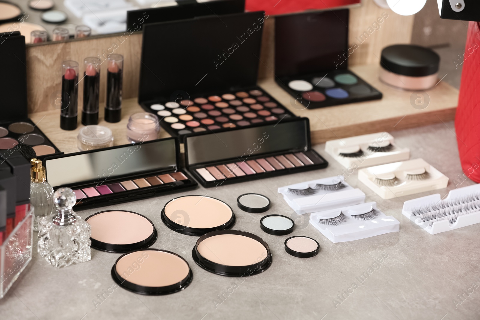 Photo of Different makeup products and accessories on dressing table in room interior