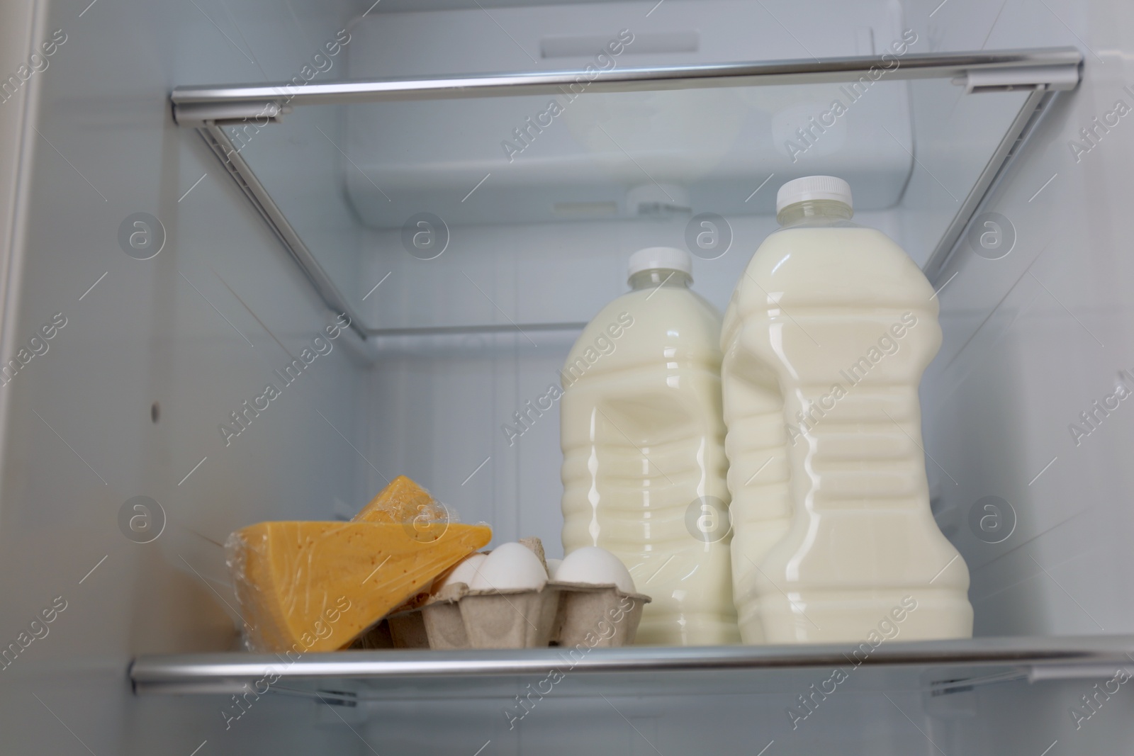 Photo of Gallons of milk, eggs and cheese in refrigerator, closeup