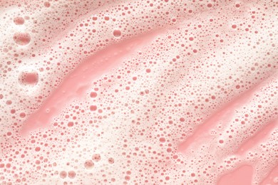 Photo of White washing foam on pale pink background, top view
