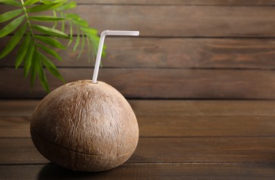 Photo of Coconut water. Fresh nut with straw on wooden table, space for text