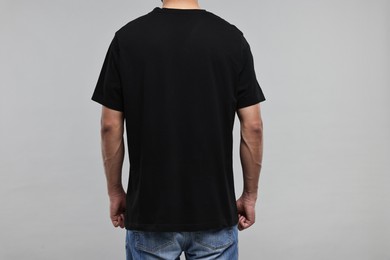 Photo of Man in black t-shirt on grey background, back view