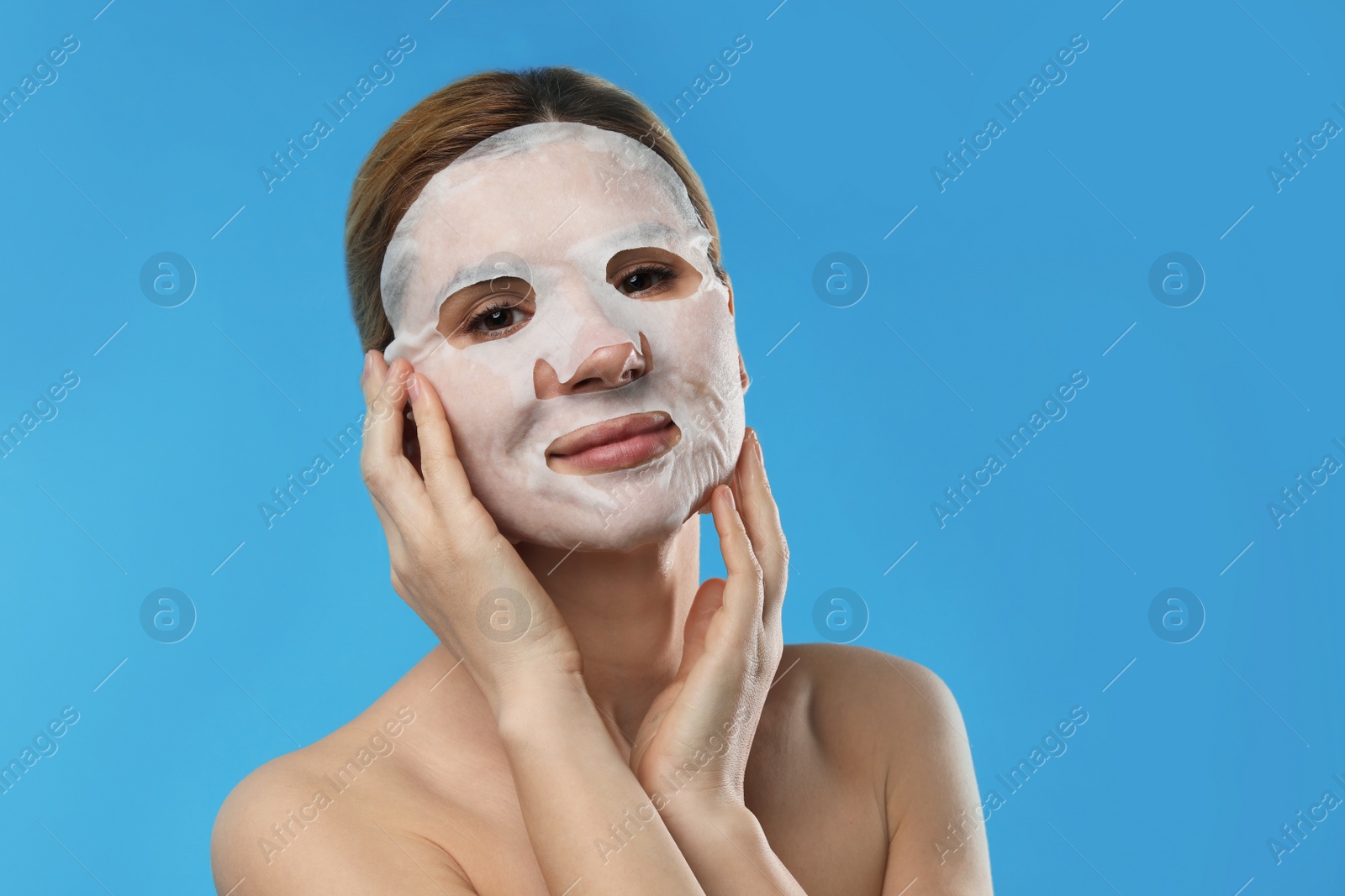 Photo of Beautiful woman with cotton mask sheet on face against color background