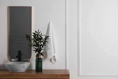 Stylish mirror over vessel sink and eucalyptus branches on bathroom vanity, space for text. Interior design