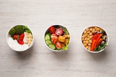 Different healthy meals in paper containers on white wooden table, flat lay