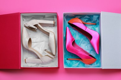 Photo of Stylish women's shoes in cardboard boxes on pink background, flat lay