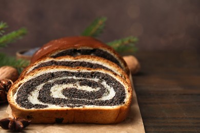 Photo of Slices of poppy seed roll and anise star on wooden table, closeup with space for text. Tasty cake