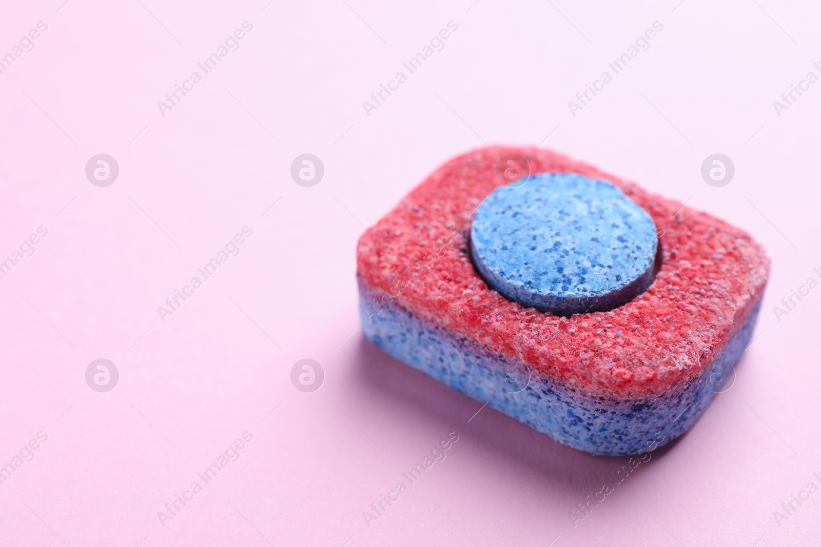 Photo of Dishwasher detergent tablet on pink background, closeup. Space for text