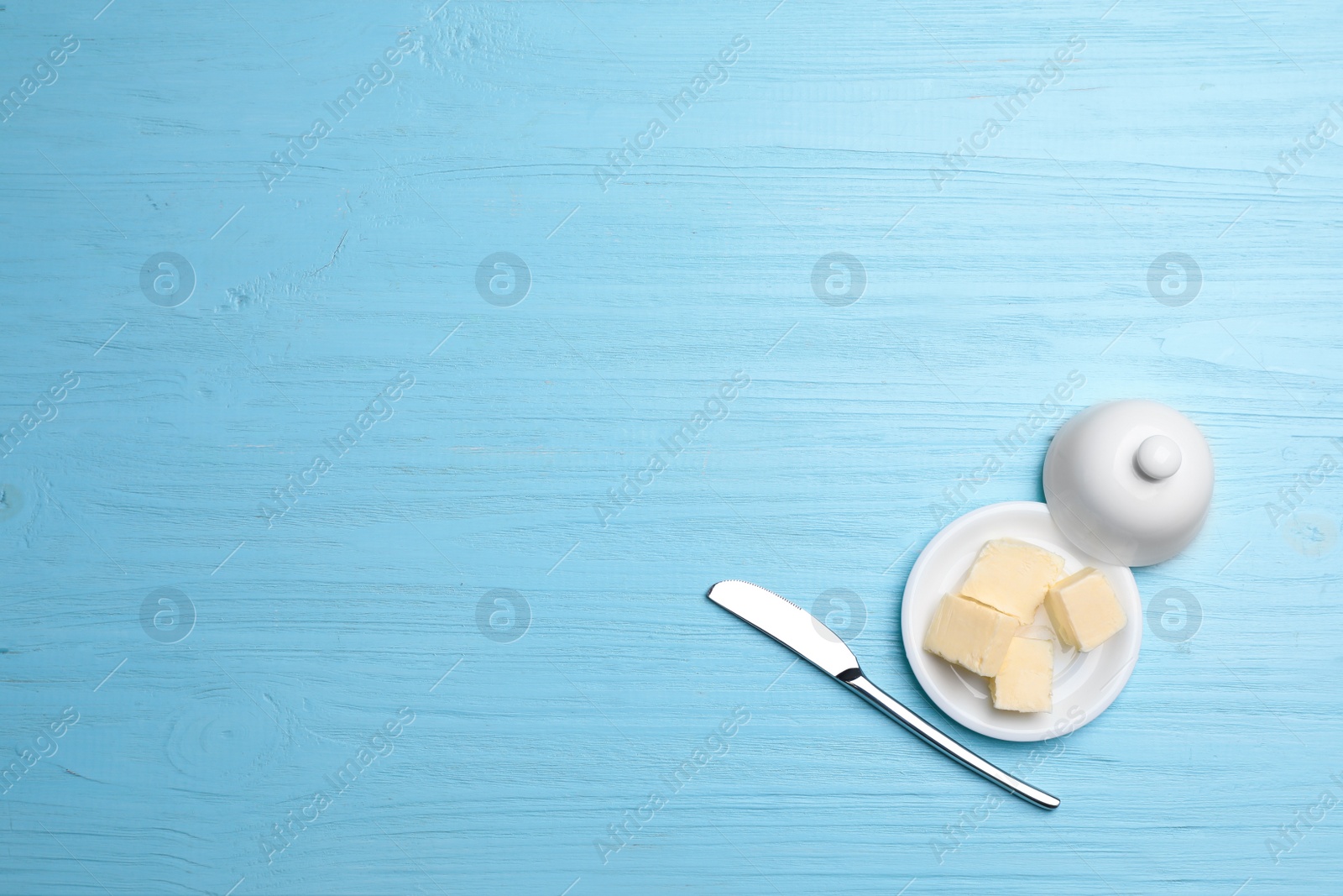 Photo of Dish with tasty fresh butter and knife on color wooden background, top view