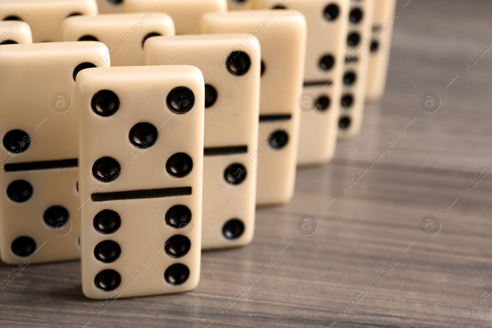 Photo of Domino tiles on wooden table, closeup. Space for text