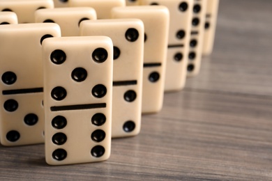 Photo of Domino tiles on wooden table, closeup. Space for text