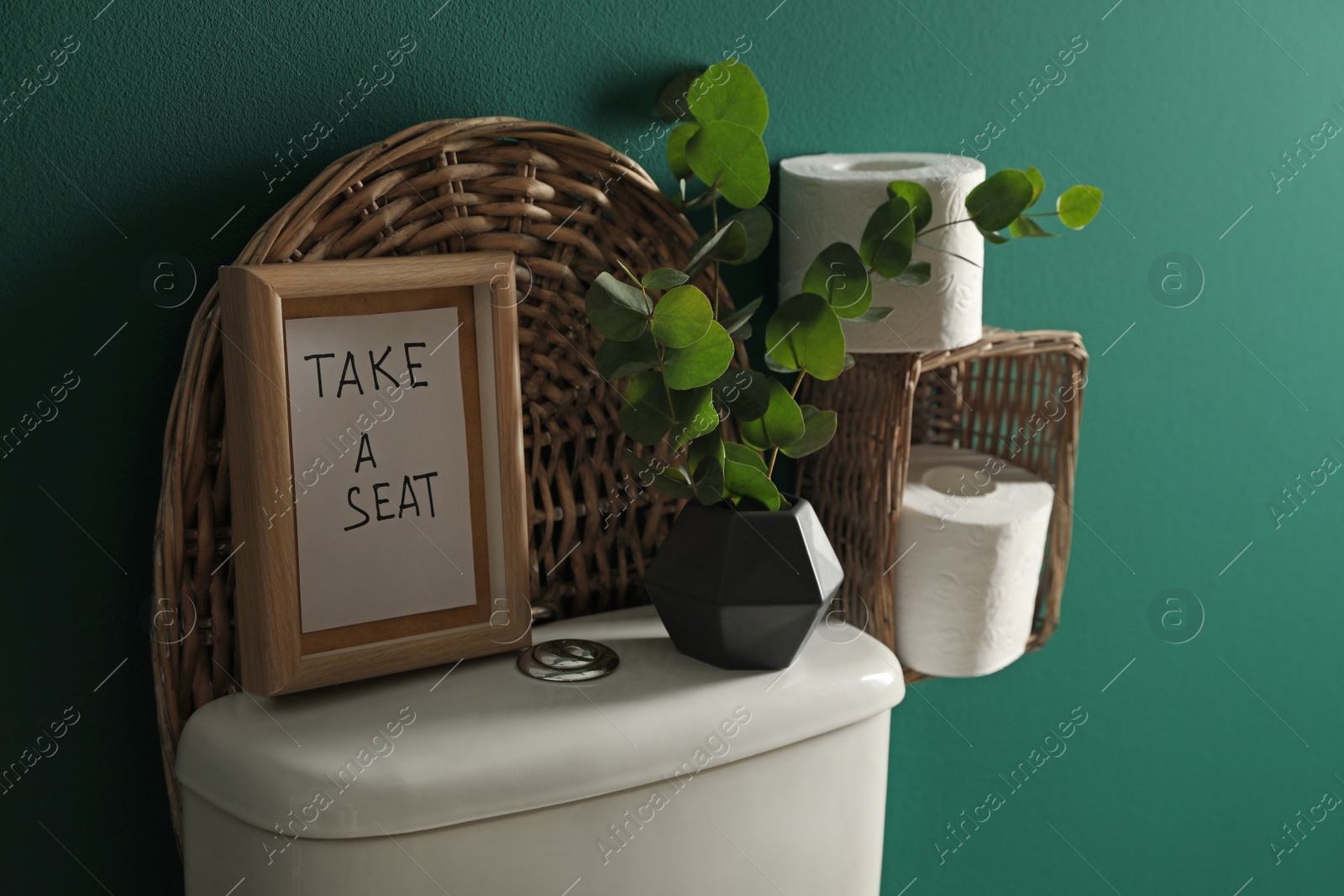 Photo of Decor elements, paper rolls and toilet bowl near green wall. Bathroom interior