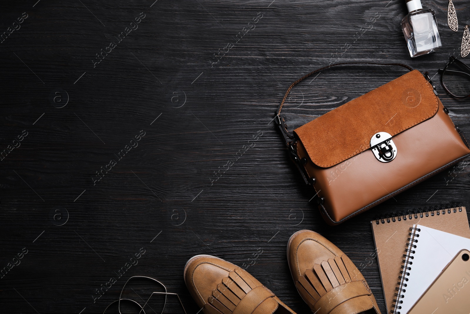 Photo of Flat lay composition with stylish shoes, woman's bag and smartphone on black wooden table. Space for text