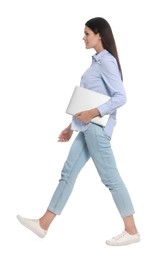 Young woman with laptop walking on white background