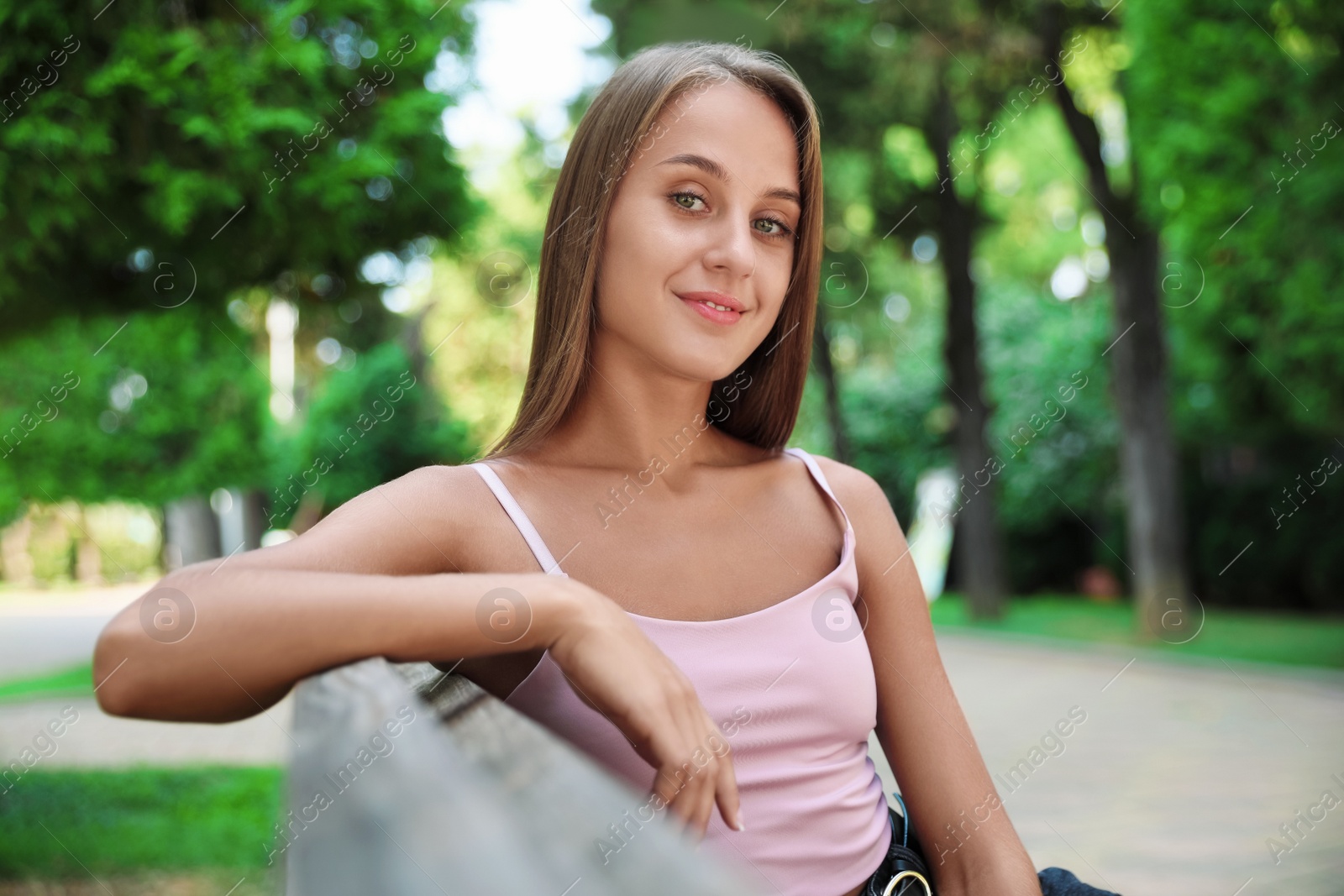 Photo of Beautiful young woman sitting on bench in park