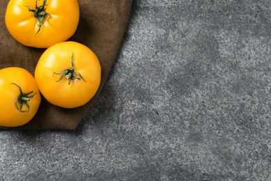 Photo of Fresh ripe yellow tomatoes on grey table, top view. Space for text