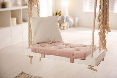Photo of Beautiful swing with pillow in room. Stylish interior design