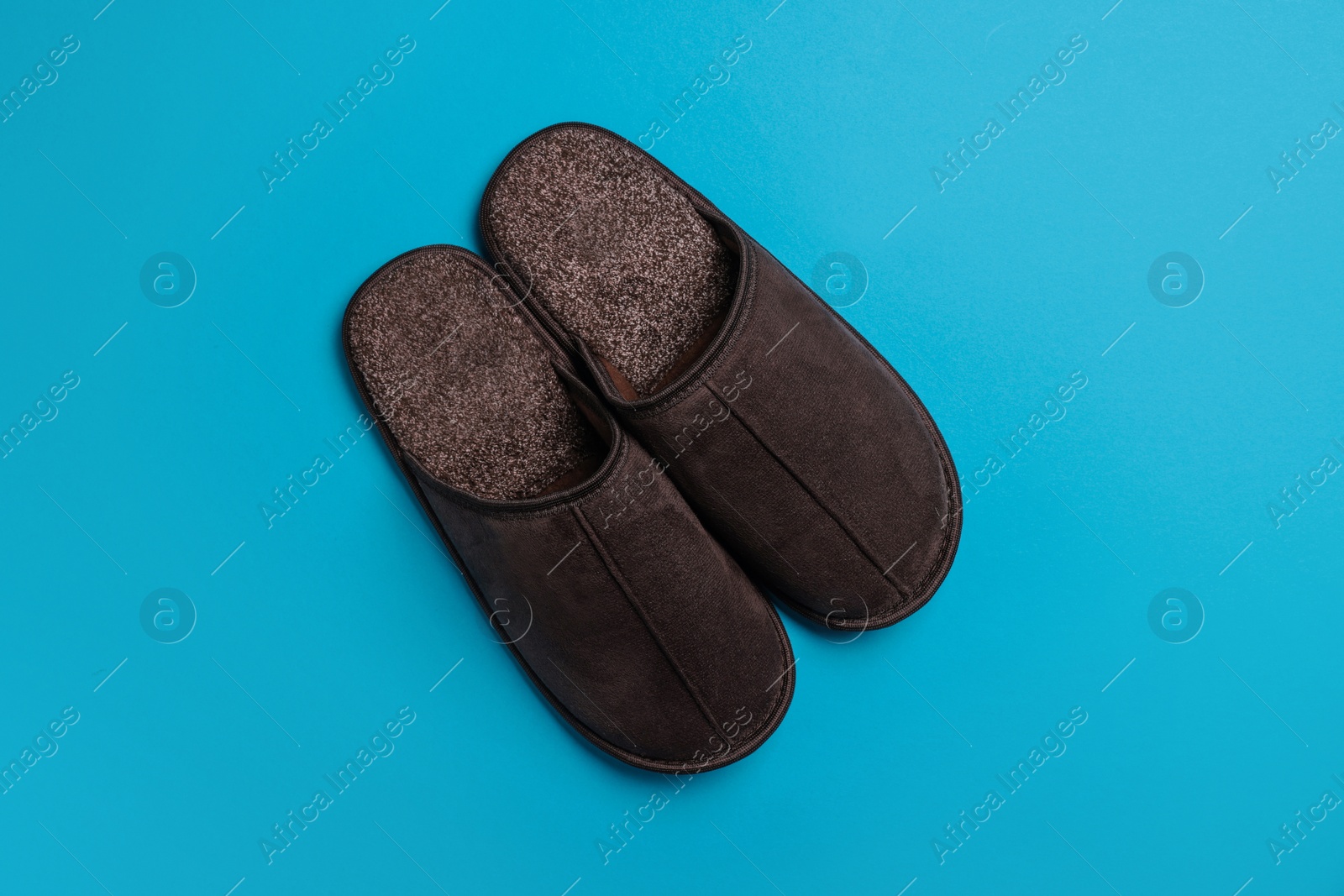 Photo of Pair of brown slippers on light blue background, top view