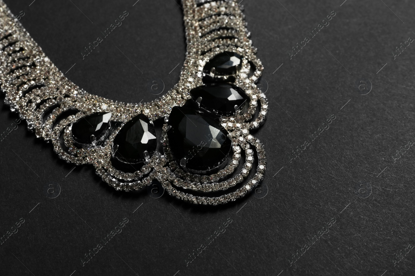 Photo of Stylish necklace with gemstones on black background, space for text. Luxury jewelry