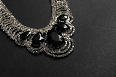 Photo of Stylish necklace with gemstones on black background, space for text. Luxury jewelry