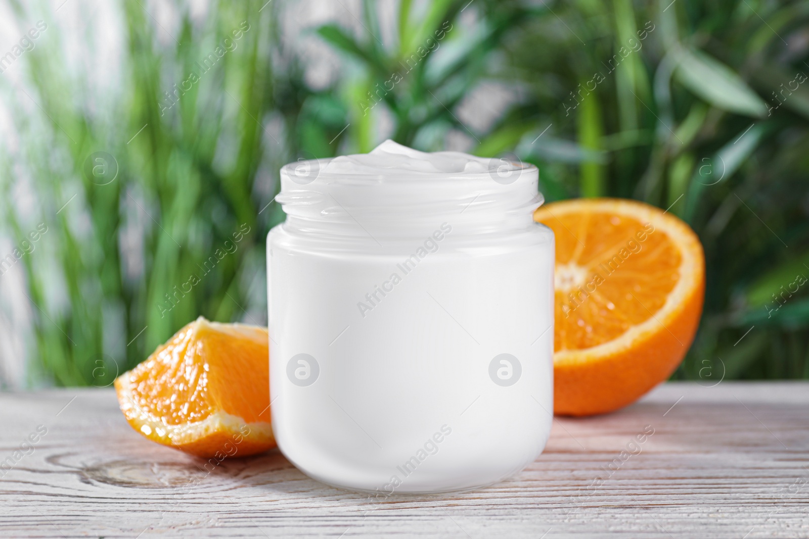 Photo of Jar of hand cream and orange on white wooden table