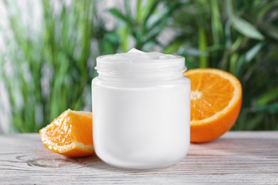 Jar of hand cream and orange on white wooden table