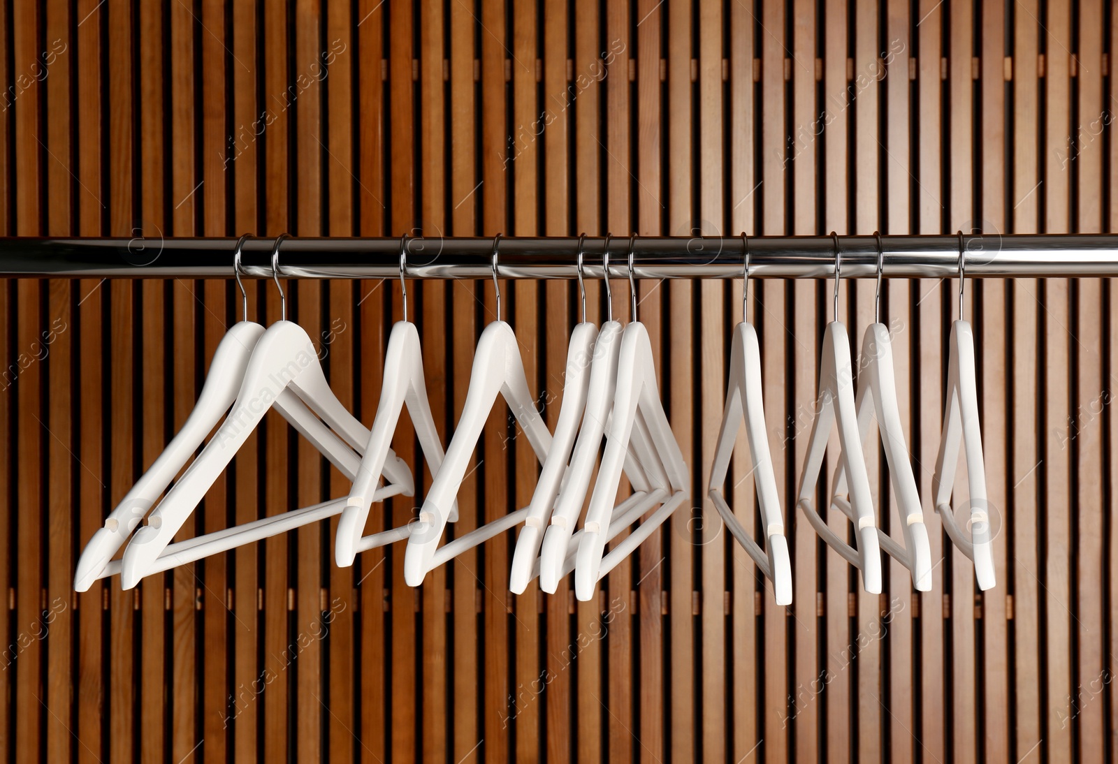 Photo of Empty hangers on rail against wooden background