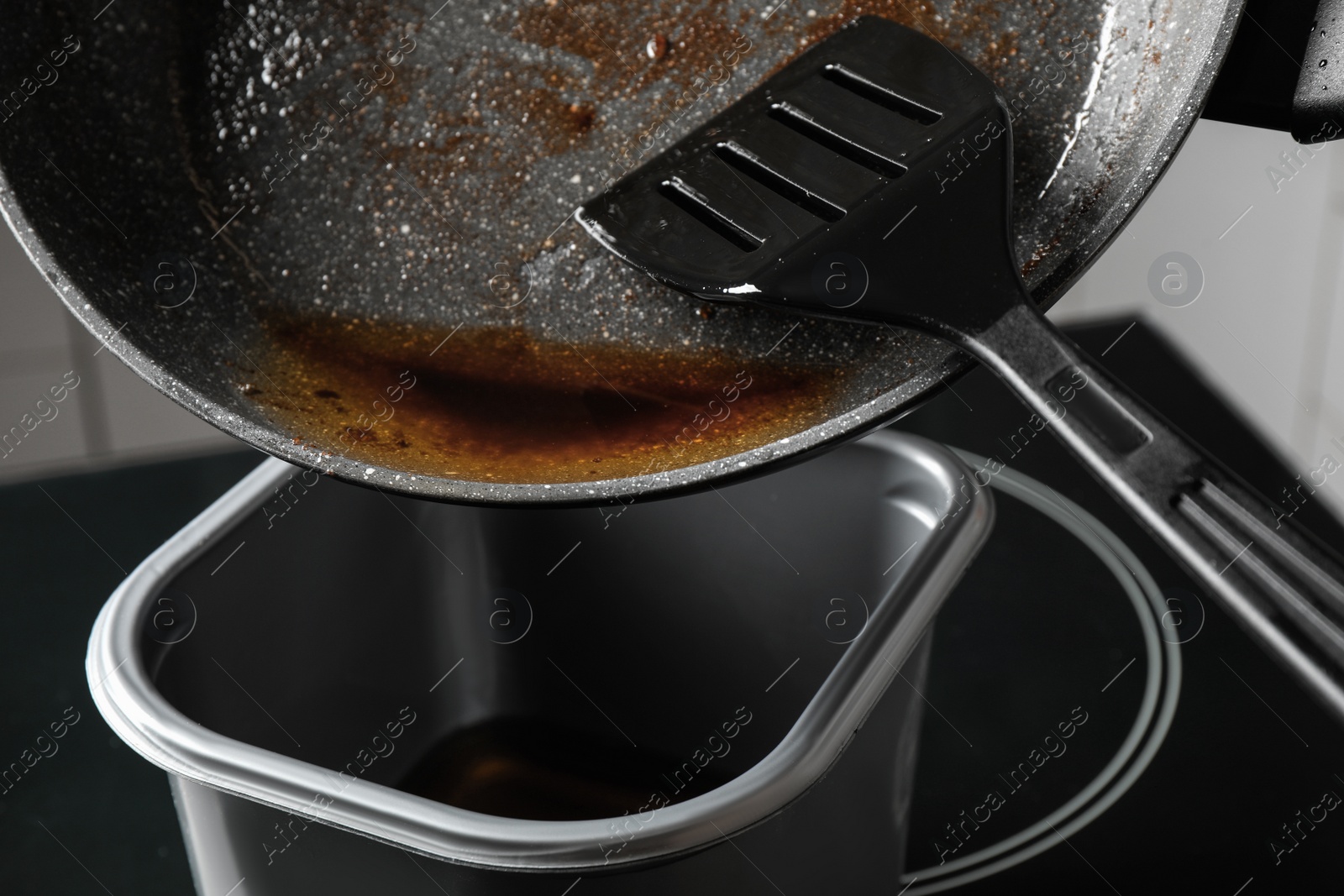 Photo of Pouring used cooking oil from frying pan into container, closeup