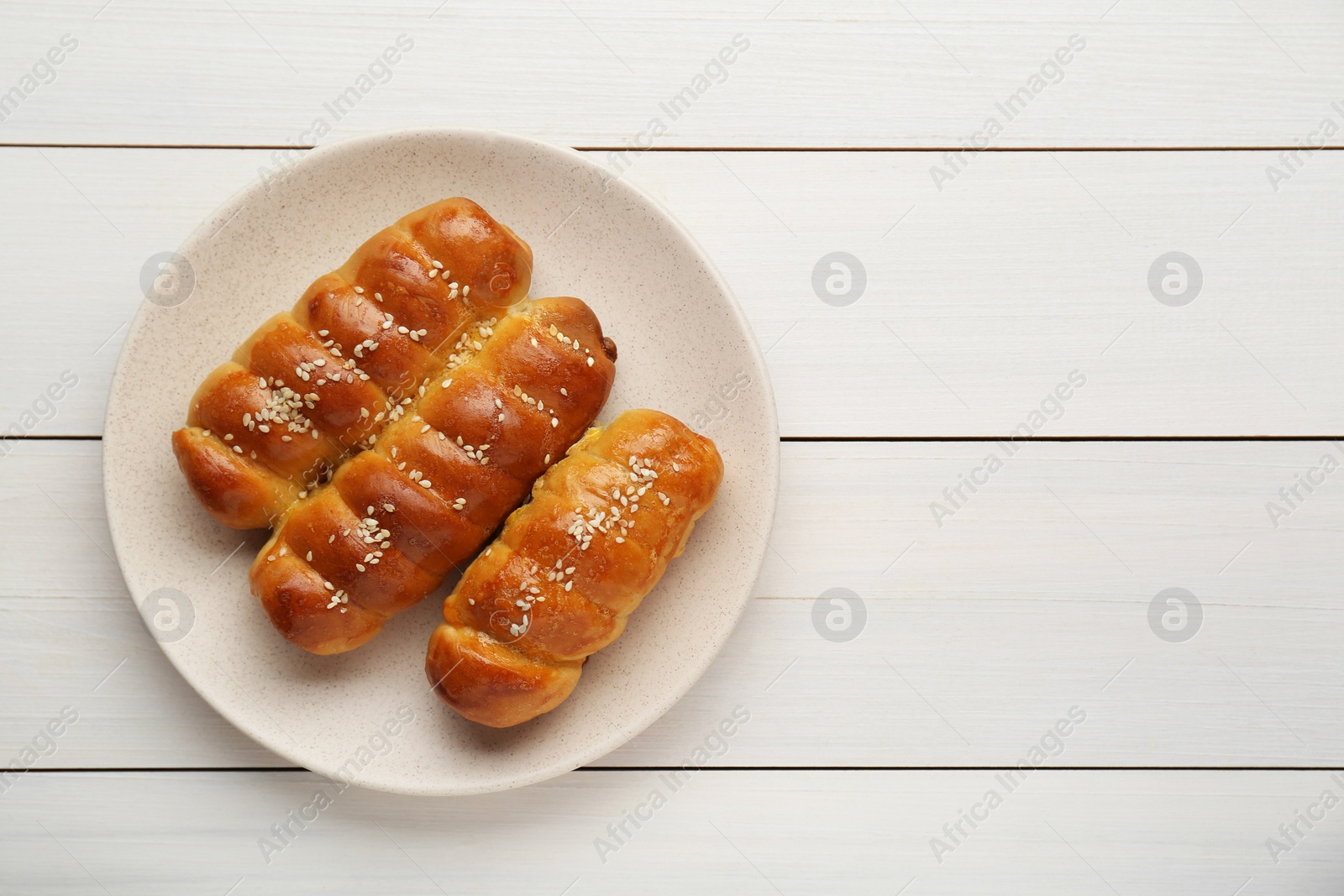 Photo of Delicious sausage rolls on white wooden table, top view. Space for text