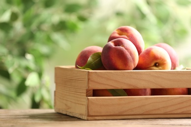 Photo of Fresh sweet peaches in wooden crate on table outdoors