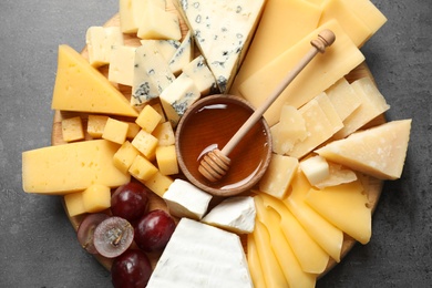 Different types of delicious cheese and snacks served on grey table, top view