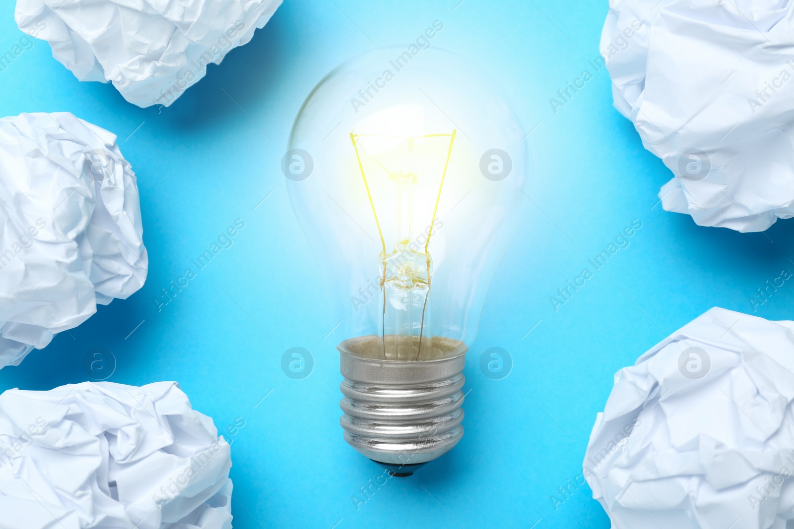 Photo of Creative flat lay composition with lightbulb and paper balls on light blue background. Idea concept