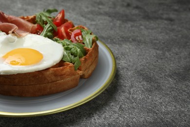 Fresh Belgian waffle with fried egg, arugula, tomatoes and jamon on grey table. Space for text