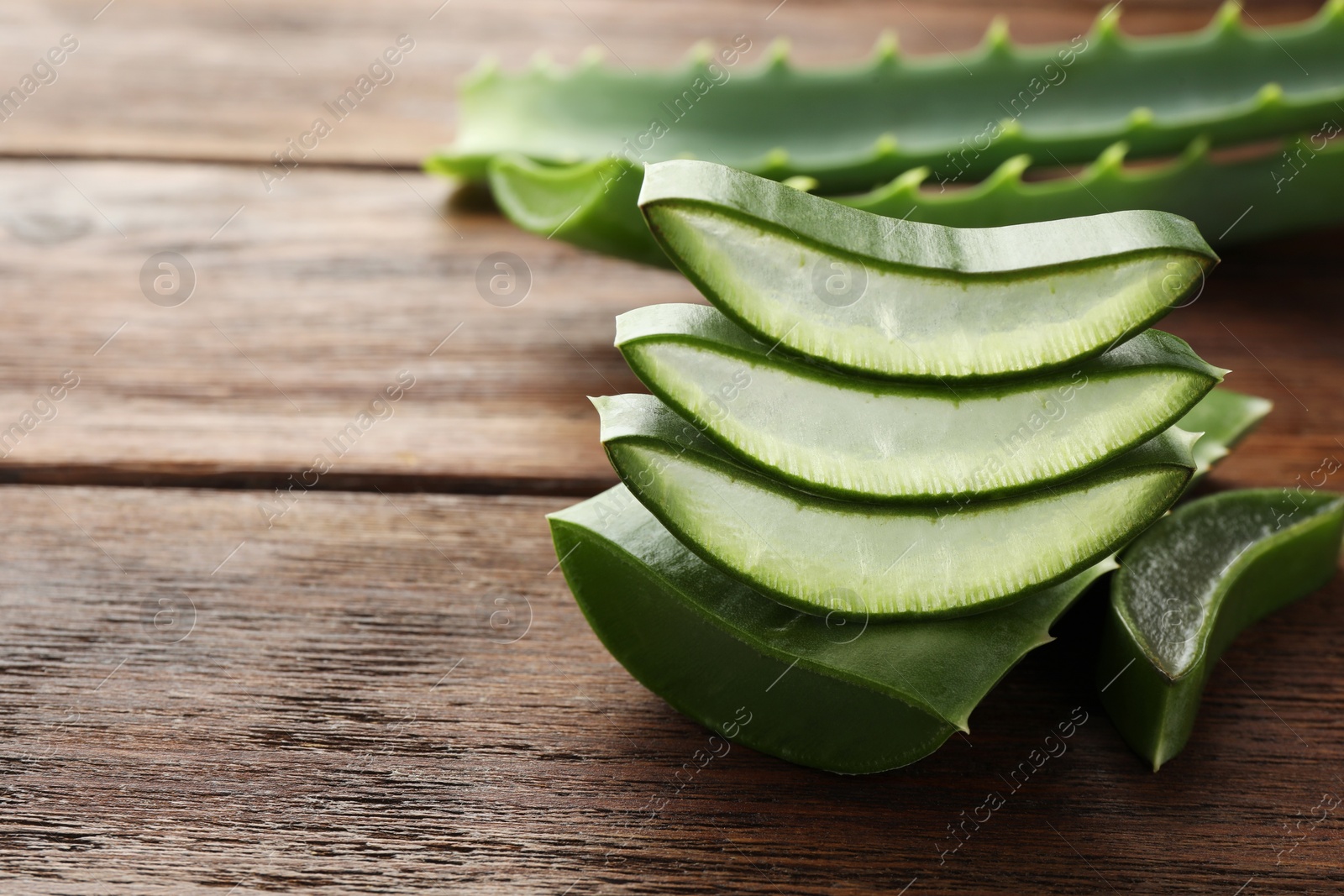 Photo of Fresh aloe vera slices on wooden table, closeup. Space for text