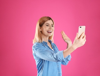 Photo of Woman using mobile phone for video chat on color background