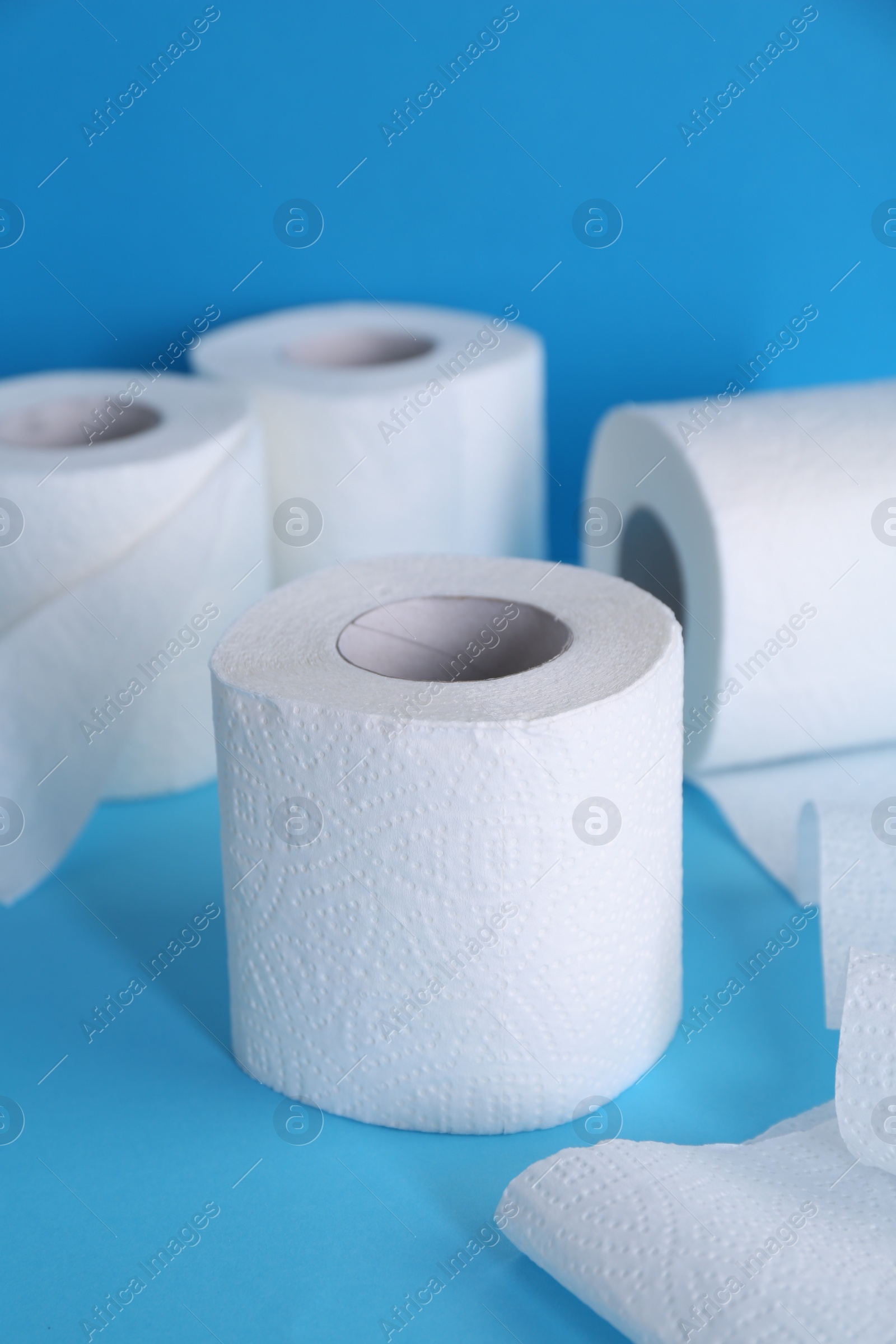 Photo of Soft toilet paper rolls on light blue background