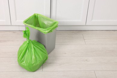 Photo of Plastic garbage bag and trash can indoors, space for text