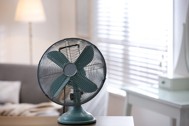 Photo of Modern electric fan on wooden table indoors. Space for text