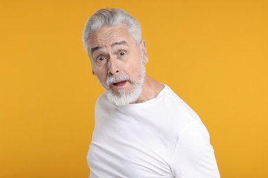 Photo of Portrait of surprised senior man on yellow background