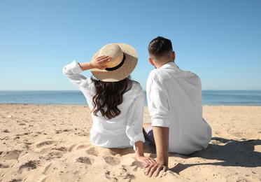 Young couple on beach near sea, back view. Honeymoon trip