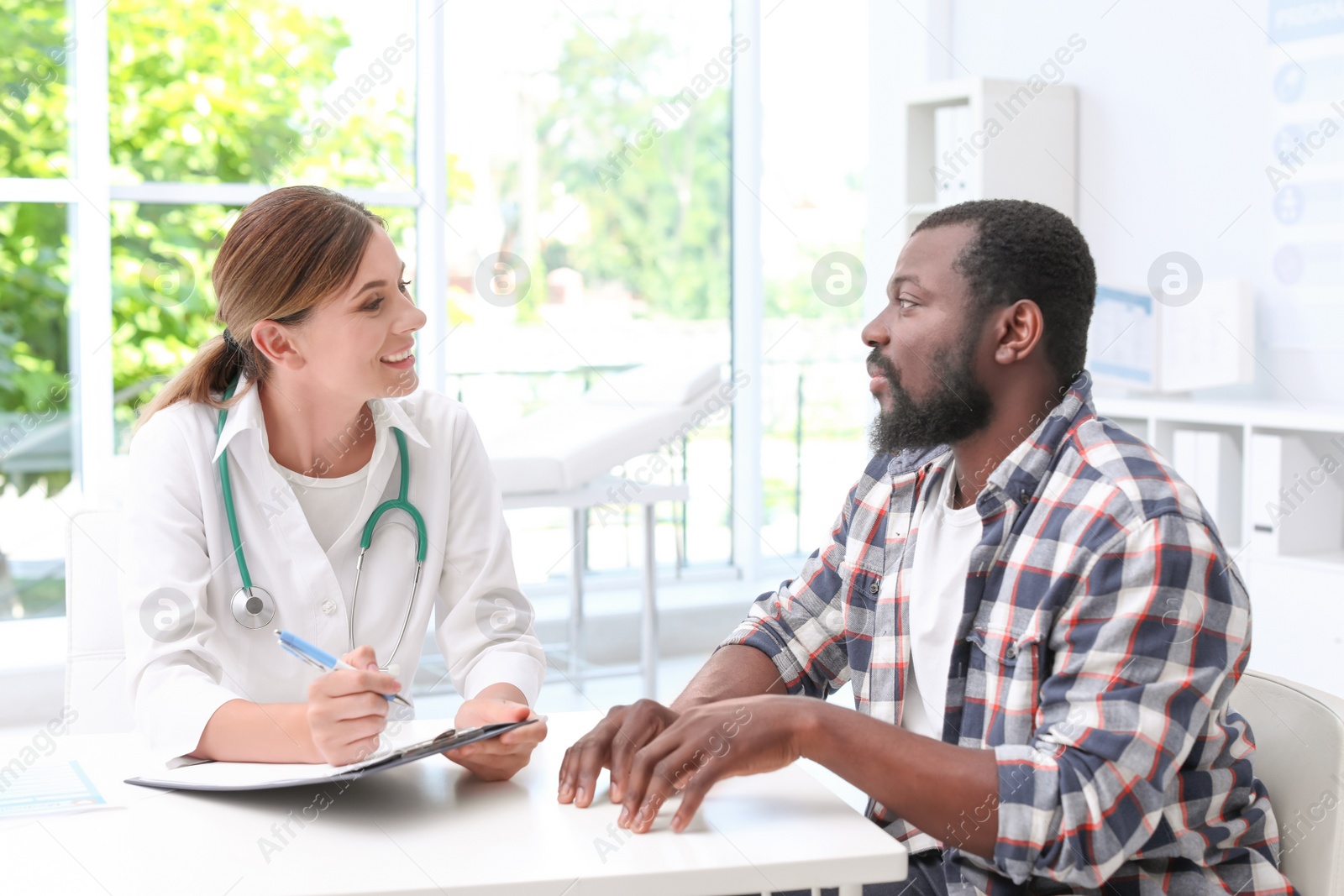 Photo of Young doctor speaking to African-American patient in hospital