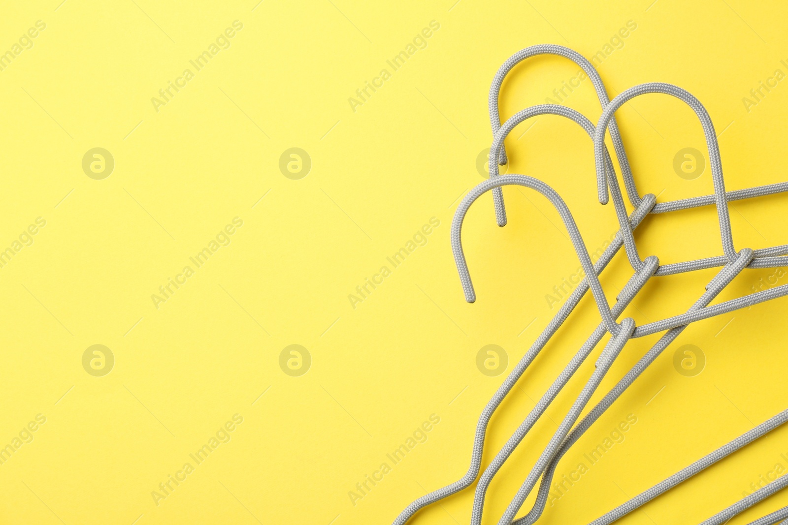 Photo of Hangers on yellow background, top view. Space for text